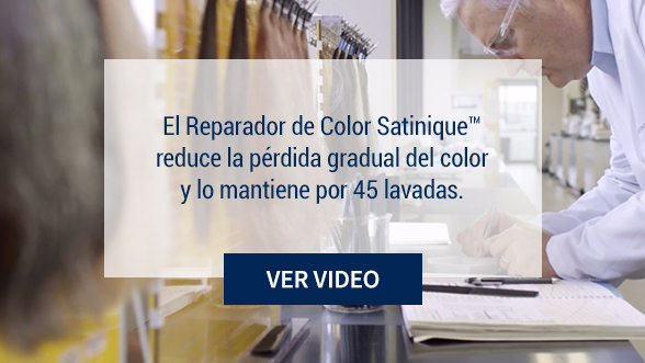 La imagen de fondo muestra un científico en un laboratorio con muestras de cabello. El Reparador de Color Satinique reduce la pérdida gradual de color del cabello.